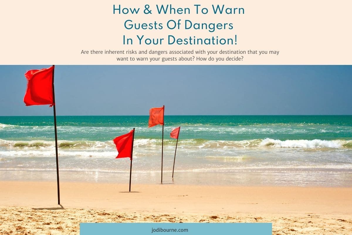 Four red flags stuck in the sand on a beach - JODI BOURNE VACATION RENTAL WEBSITE DESIGNER